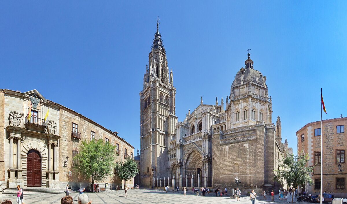 The spire and dome of Toledo Cathedral beside the Archbishop's Palace on a sunny square