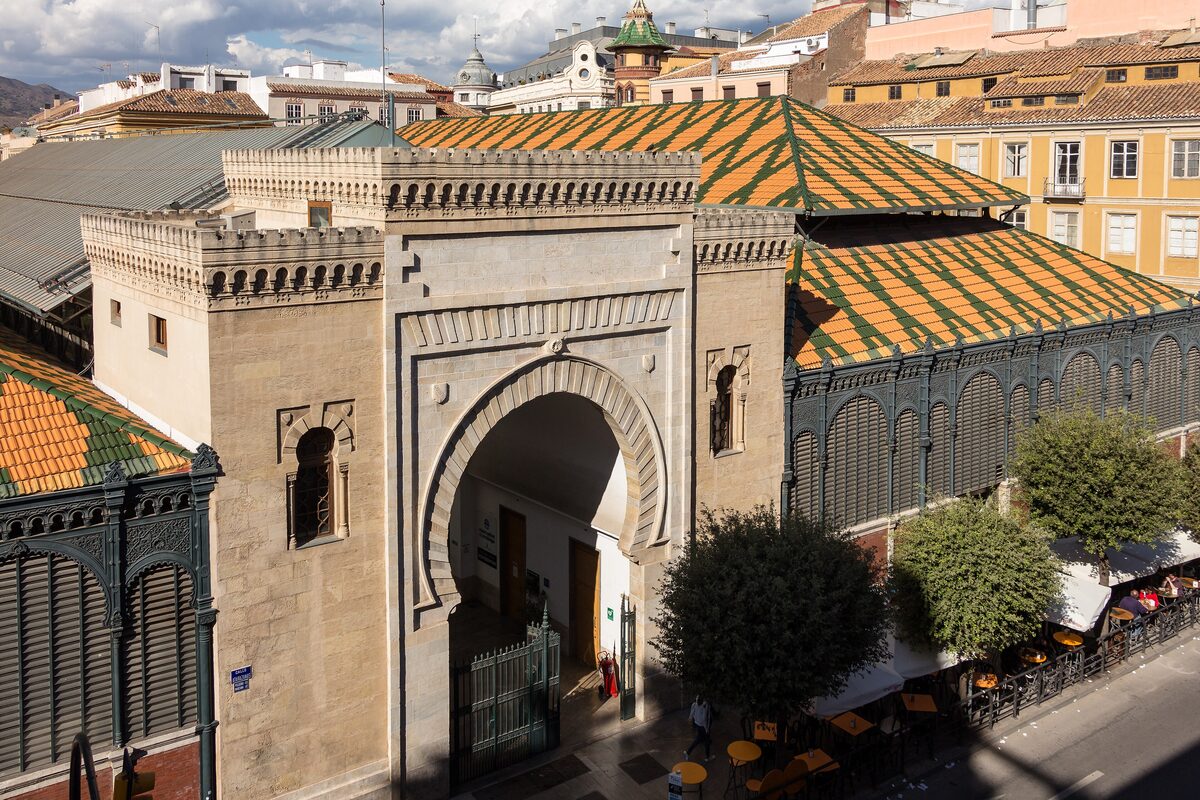 The Moorish horseshoe-arch gate of the Atarazanas market beside its green and orange tiled roofs