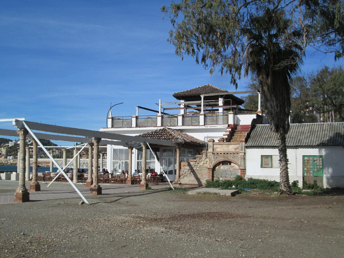 The white Baños del Carmen pavilion with its terrace and a row of old brick columns on the seafront