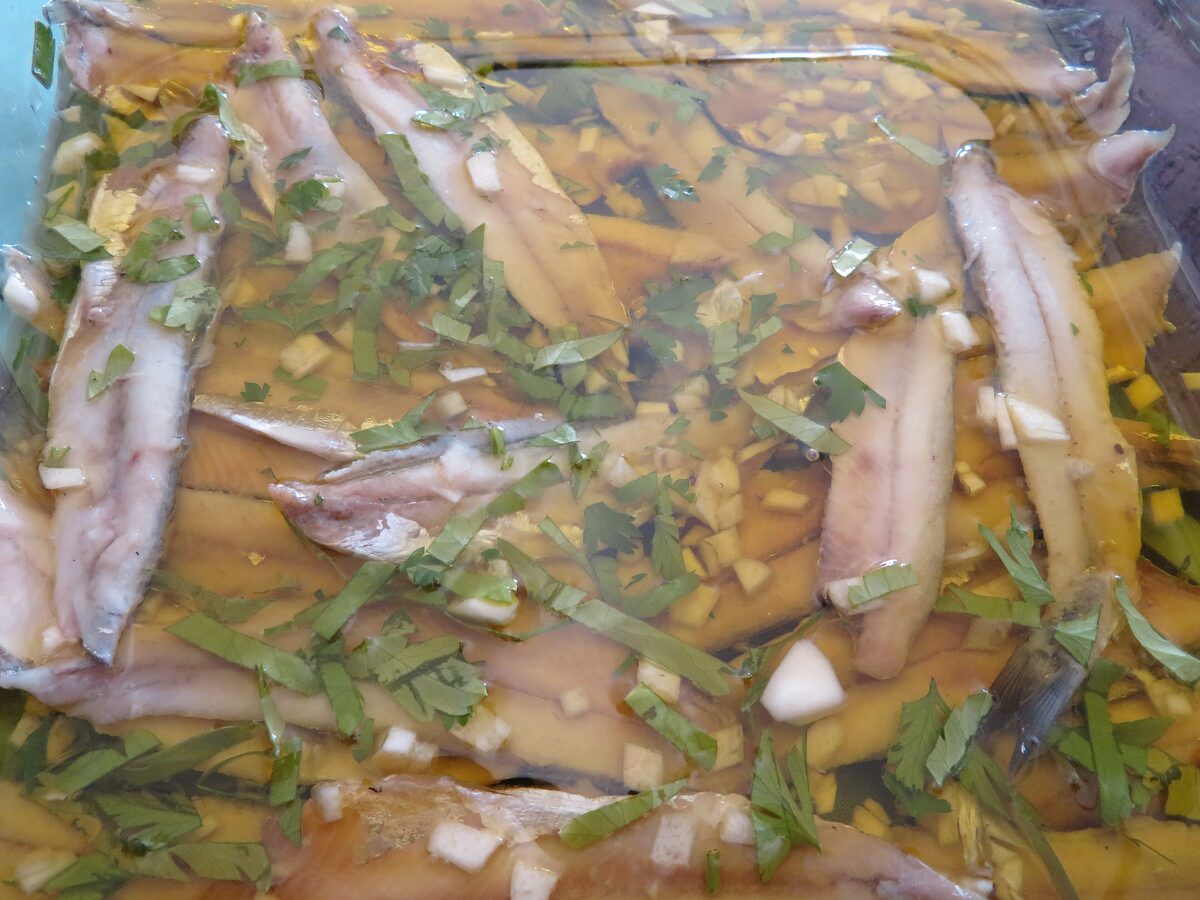 Vinegar-marinated anchovy fillets with garlic and parsley in a shallow dish