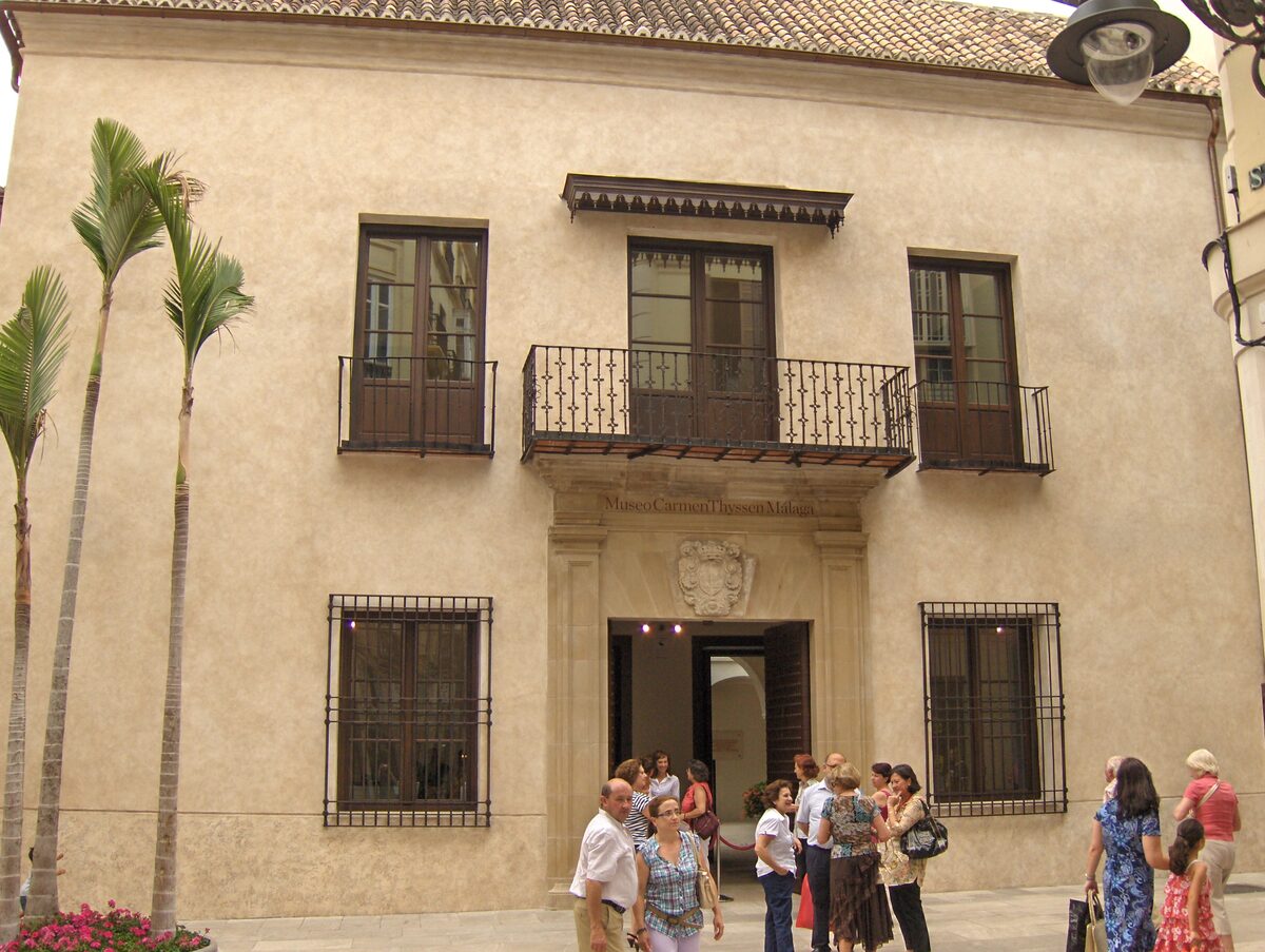 The stone facade of the Palacio de Villalón, home of the Carmen Thyssen Museum, with a wrought-iron balcony above the entrance