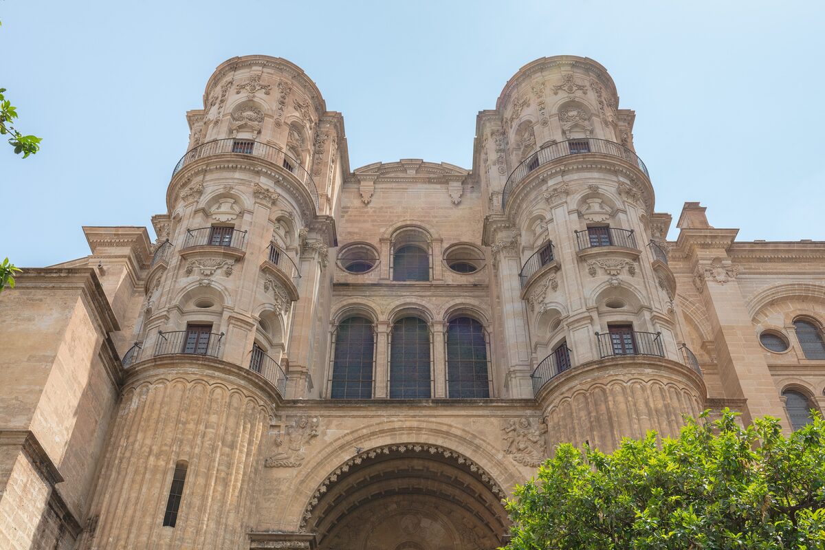 The carved sandstone facade of Málaga Cathedral: twin towers above an arched doorway