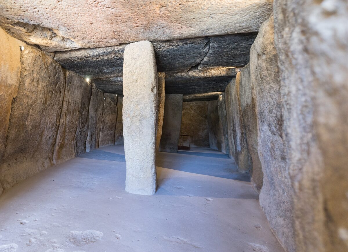 Inside the Menga dolmen, a long stone chamber with a tall upright slab and huge roof stones