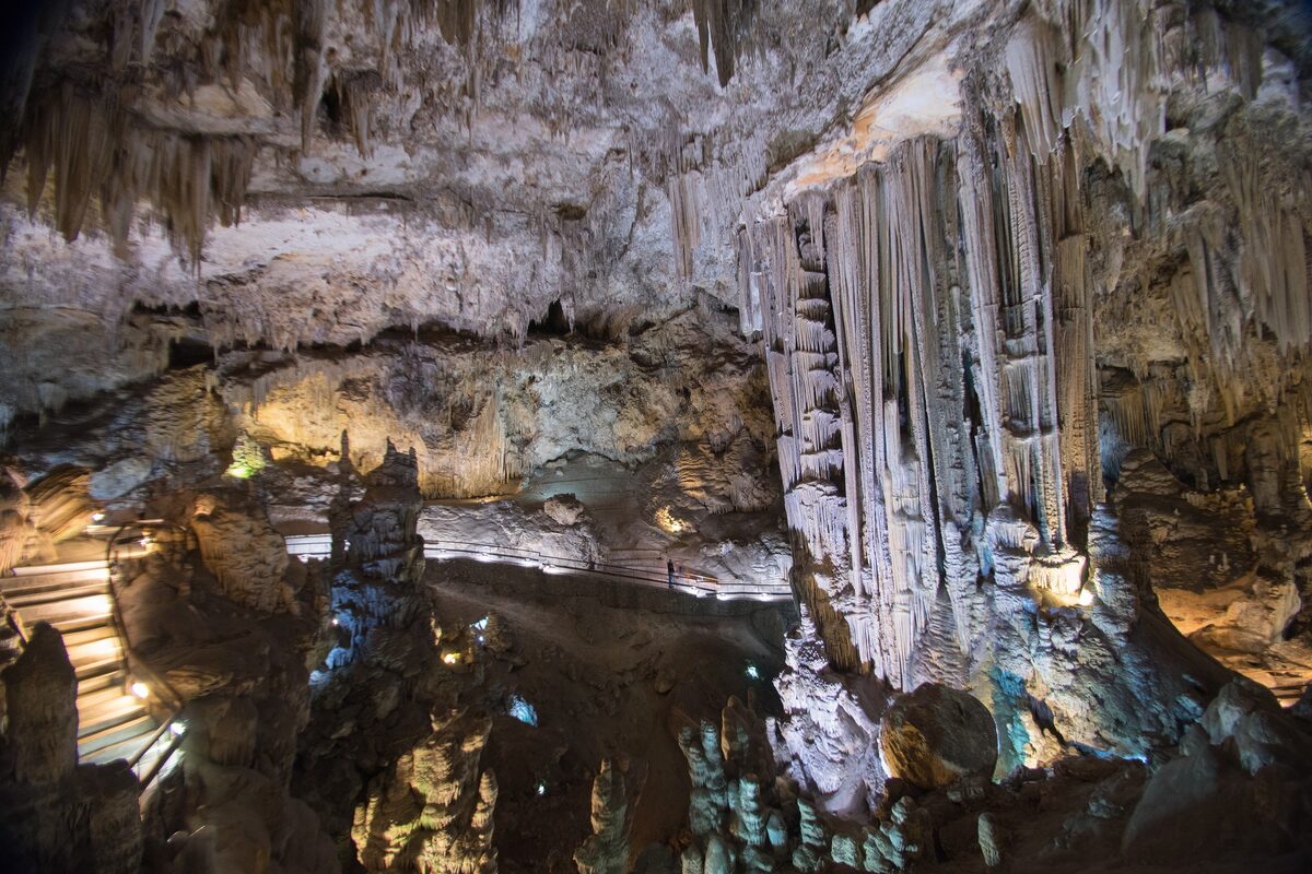 Tall stalactite curtains and rock columns inside the Nerja cave, lit along a walkway