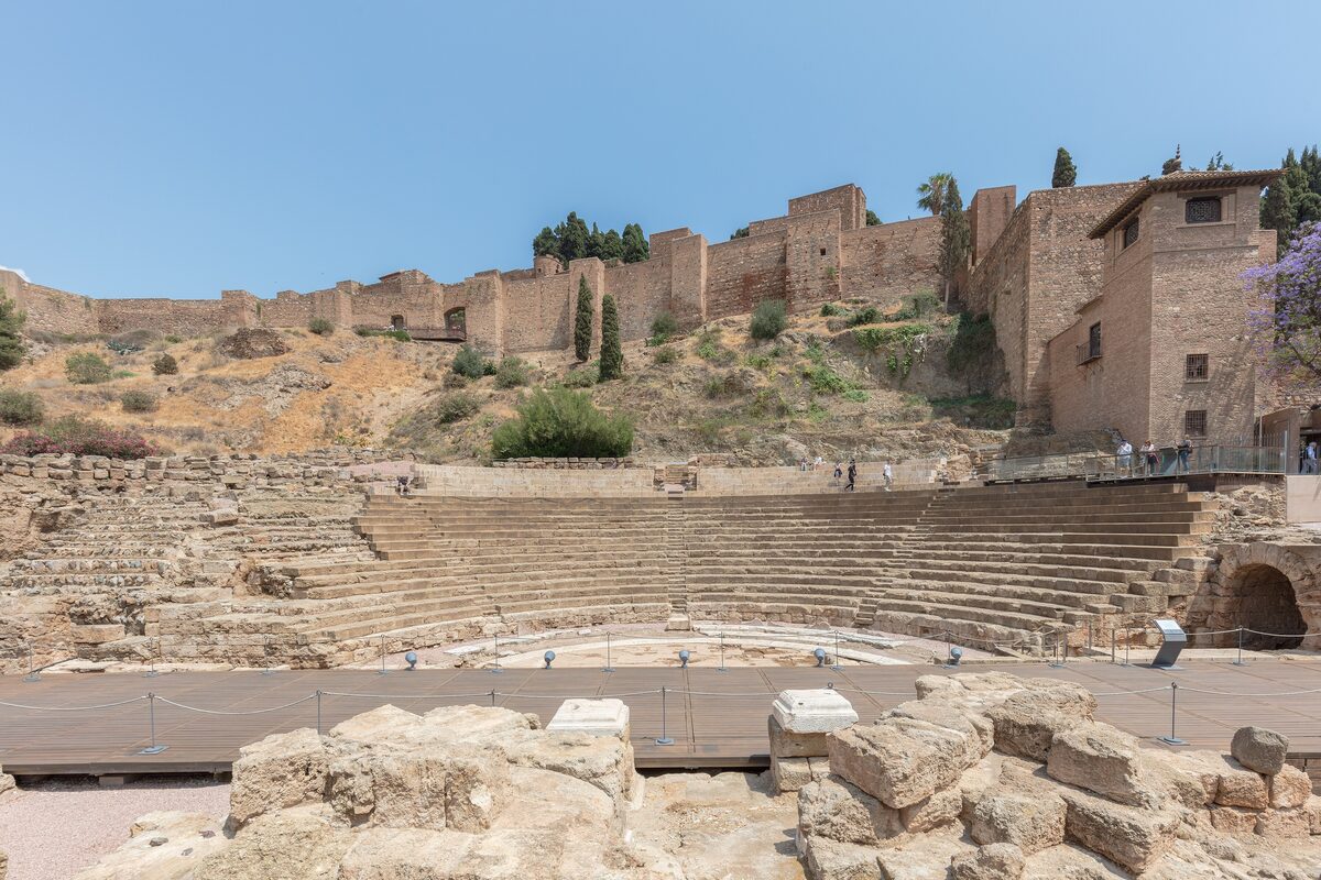 The semicircular stone tiers of the Roman theater, with the Alcazaba walls on the hill above