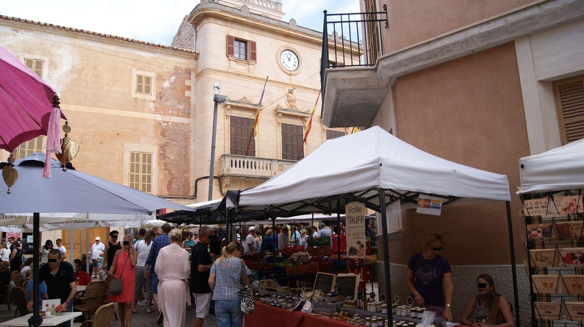 The Saturday market on Santanyí's Plaça Major, with white awnings and stalls in front of the town hall