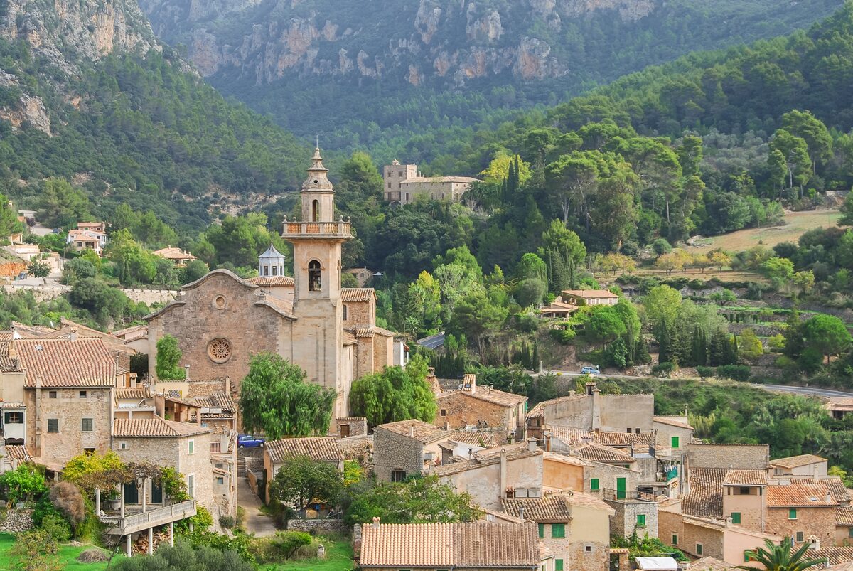 Valldemossa's stone houses and church tower below the green slopes of the Tramuntana mountains