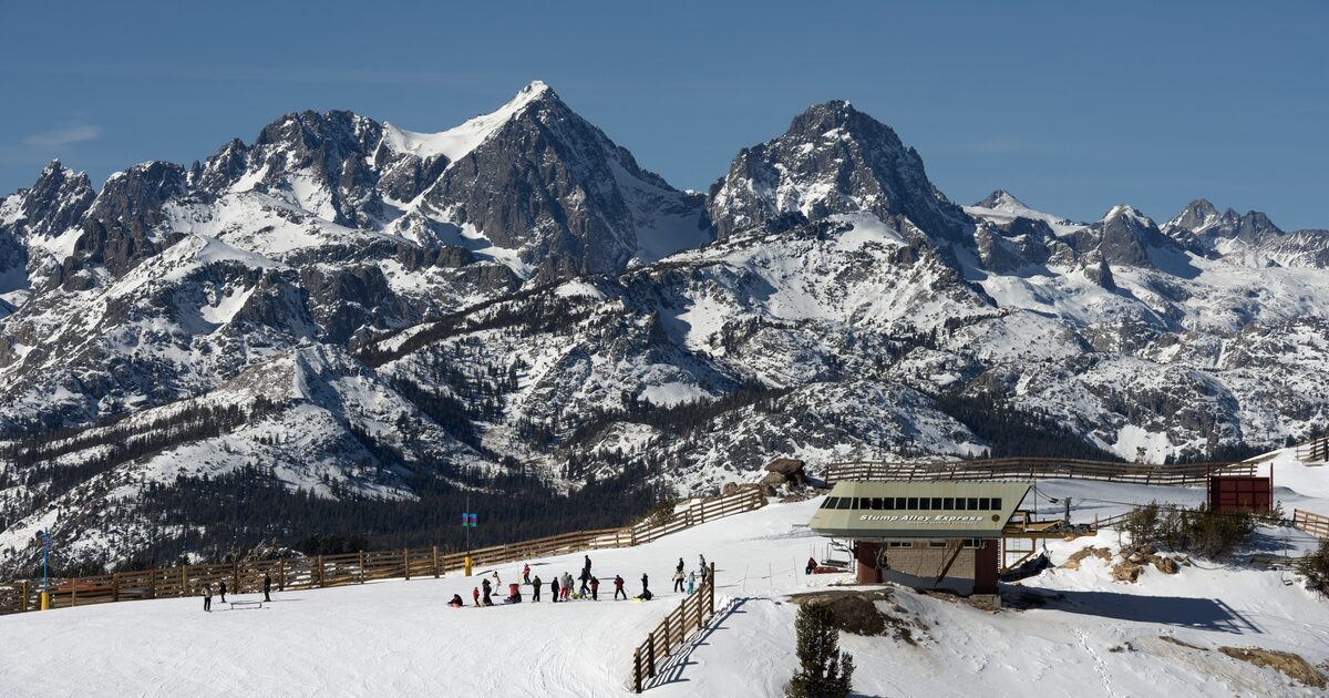 Skiers at the top of a Mammoth lift below the snowy Minarets