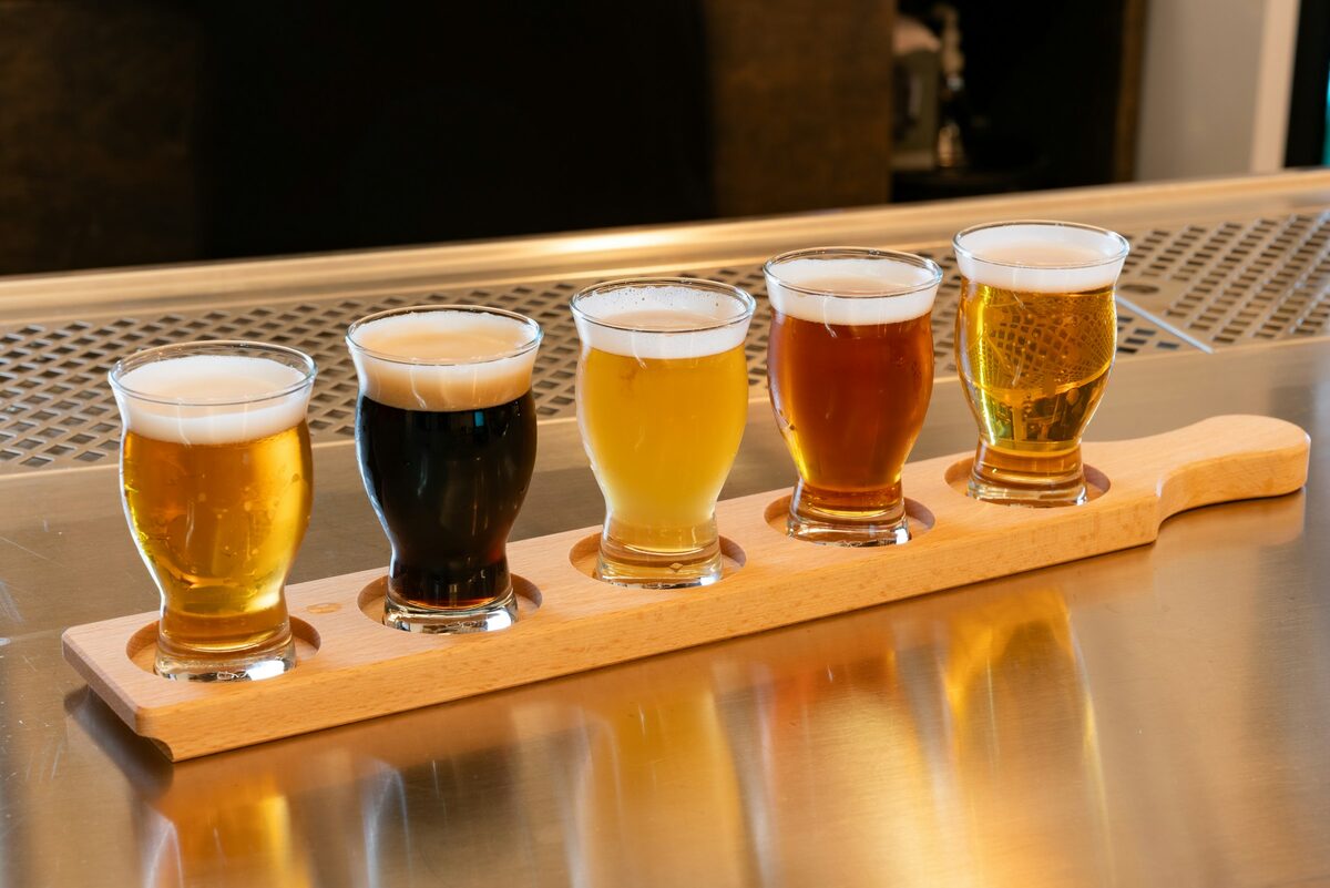 A wooden paddle holding a flight of five small glasses of beer