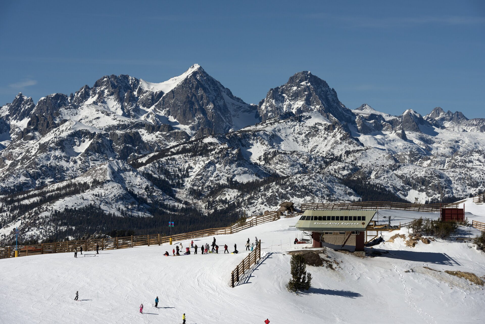 Skiers at the top of a Mammoth lift below the snowy Minarets