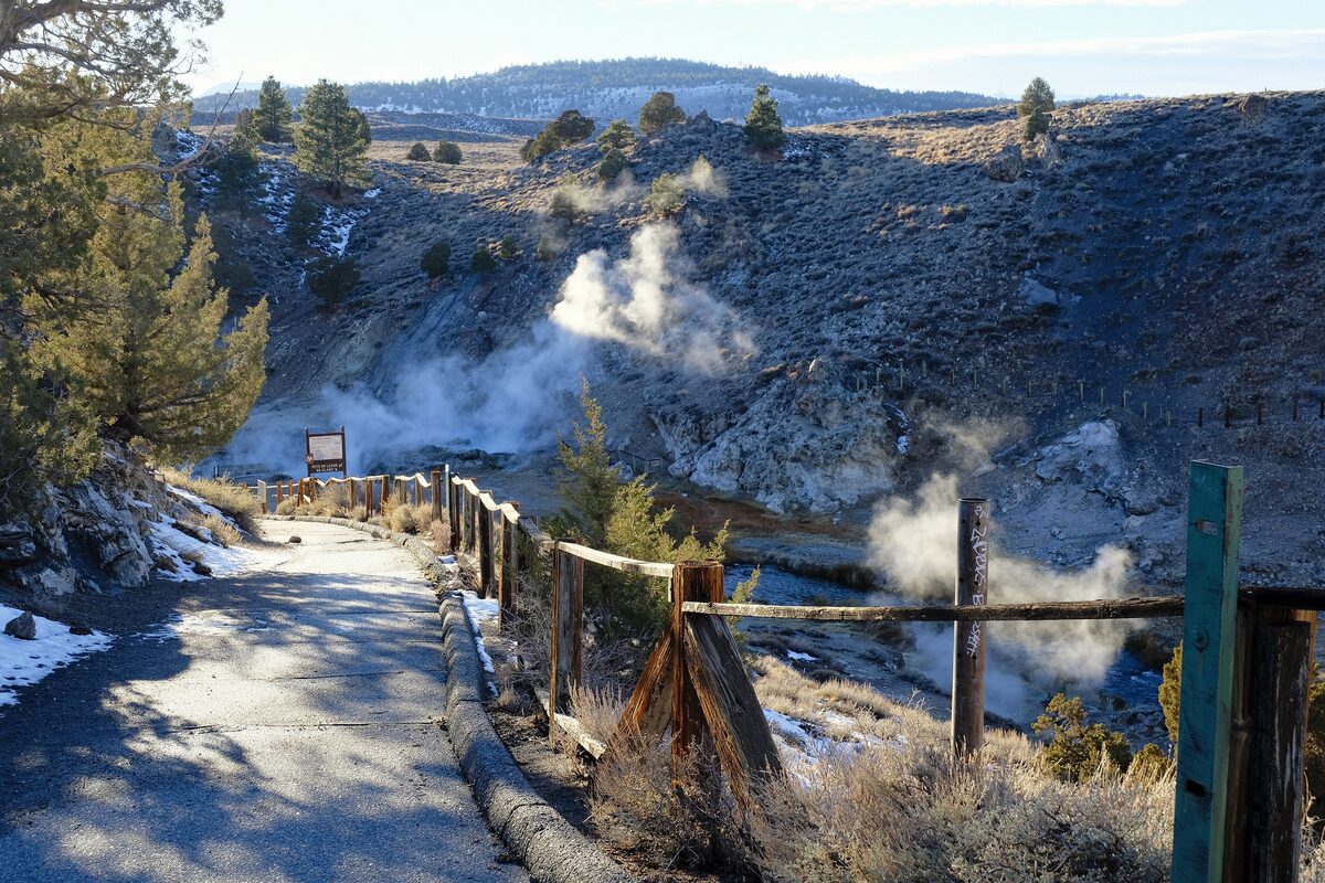 Steam rising from the Hot Creek gorge beside a snowy viewing path