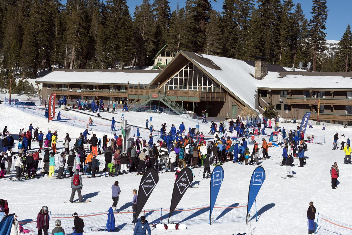 Skiers gather outside a chalet-style base lodge at Mammoth Mountain