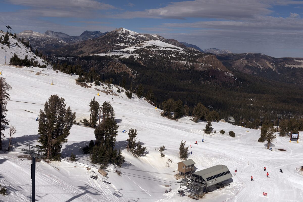 A snowy mid-mountain slope with a small lift station among pines