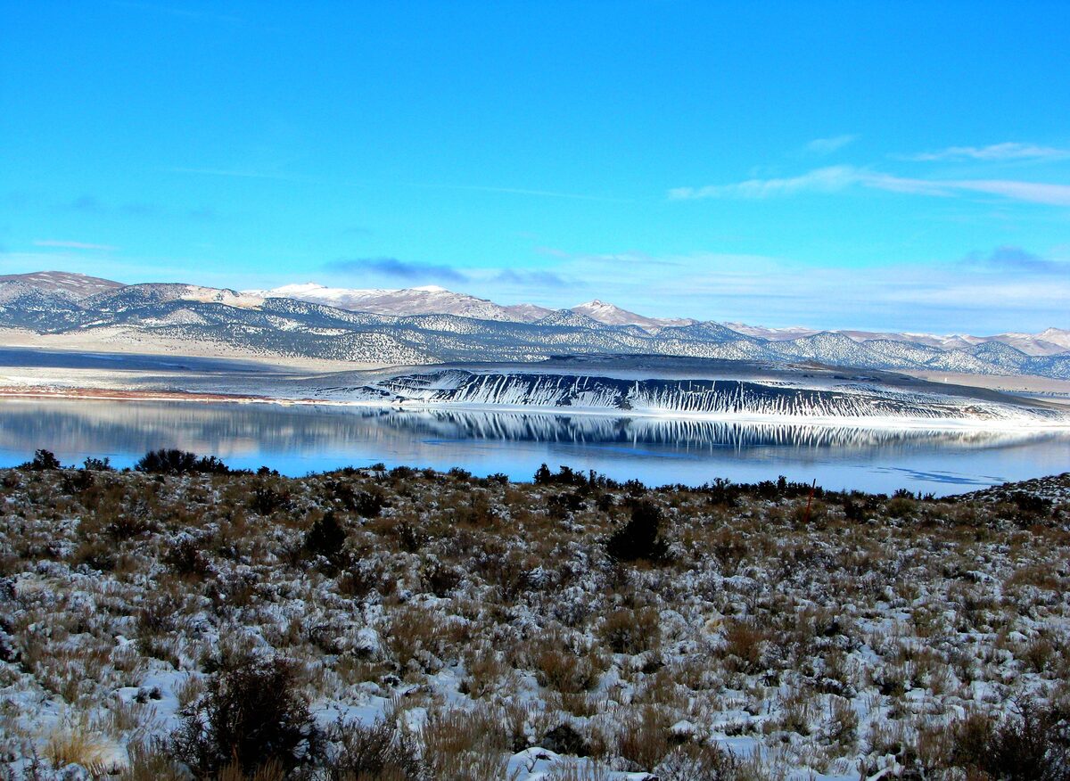 Snowy shore and the pale water of Mono Lake under blue sky
