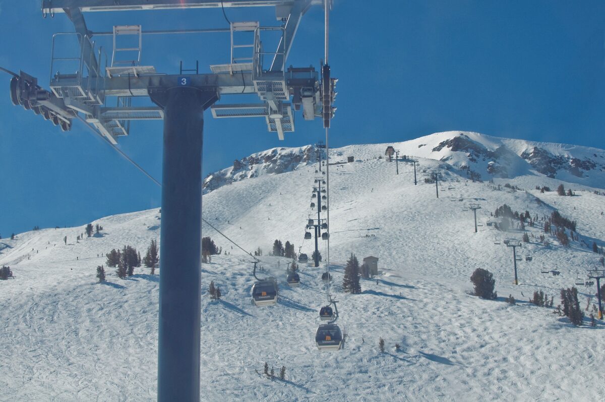 Gondola cabins climbing a snowy slope toward the top of Mammoth