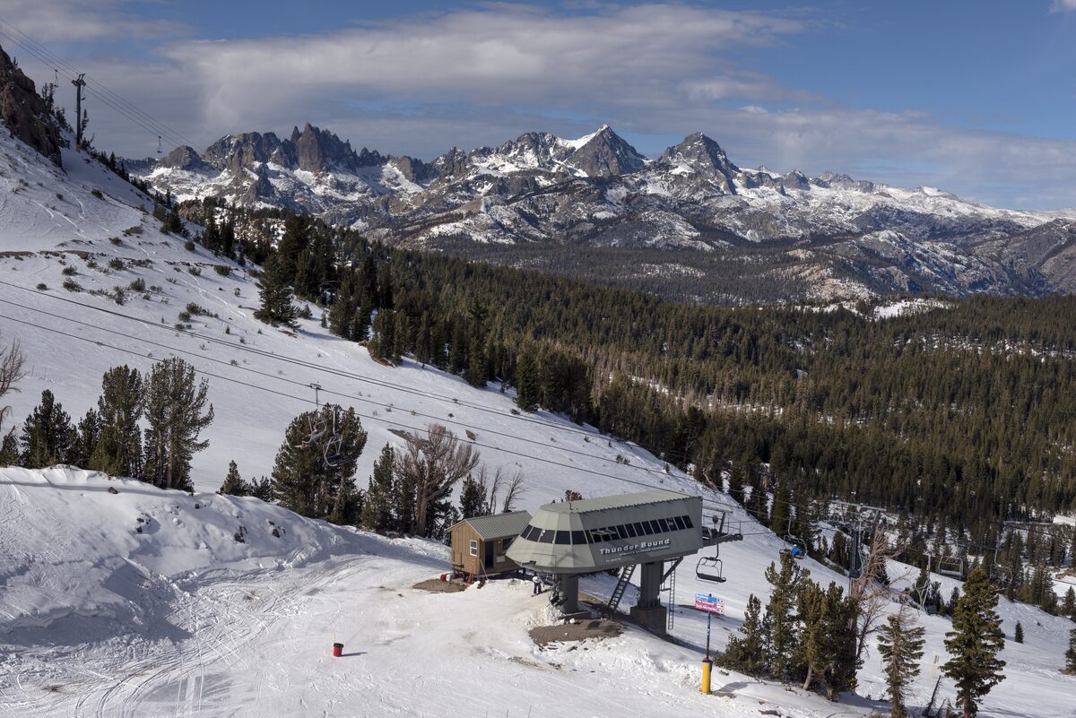 A snowy mountain slope with a chairlift terminal and the Minarets beyond