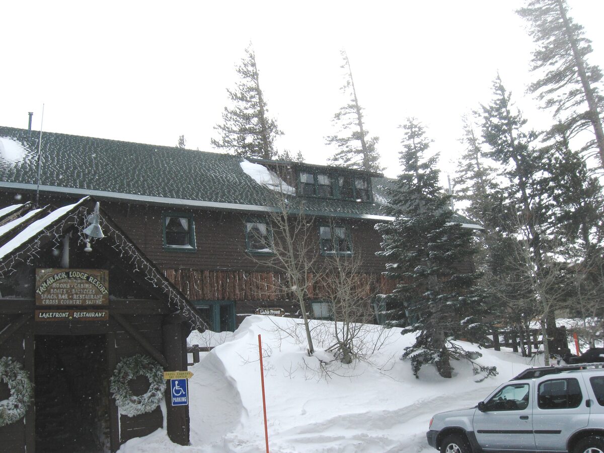 Snowbound Tamarack Lodge among tall pines beside Twin Lakes