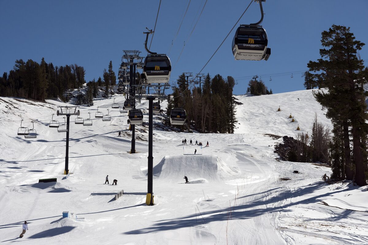 A groomed terrain park with jumps below a lift line at Mammoth