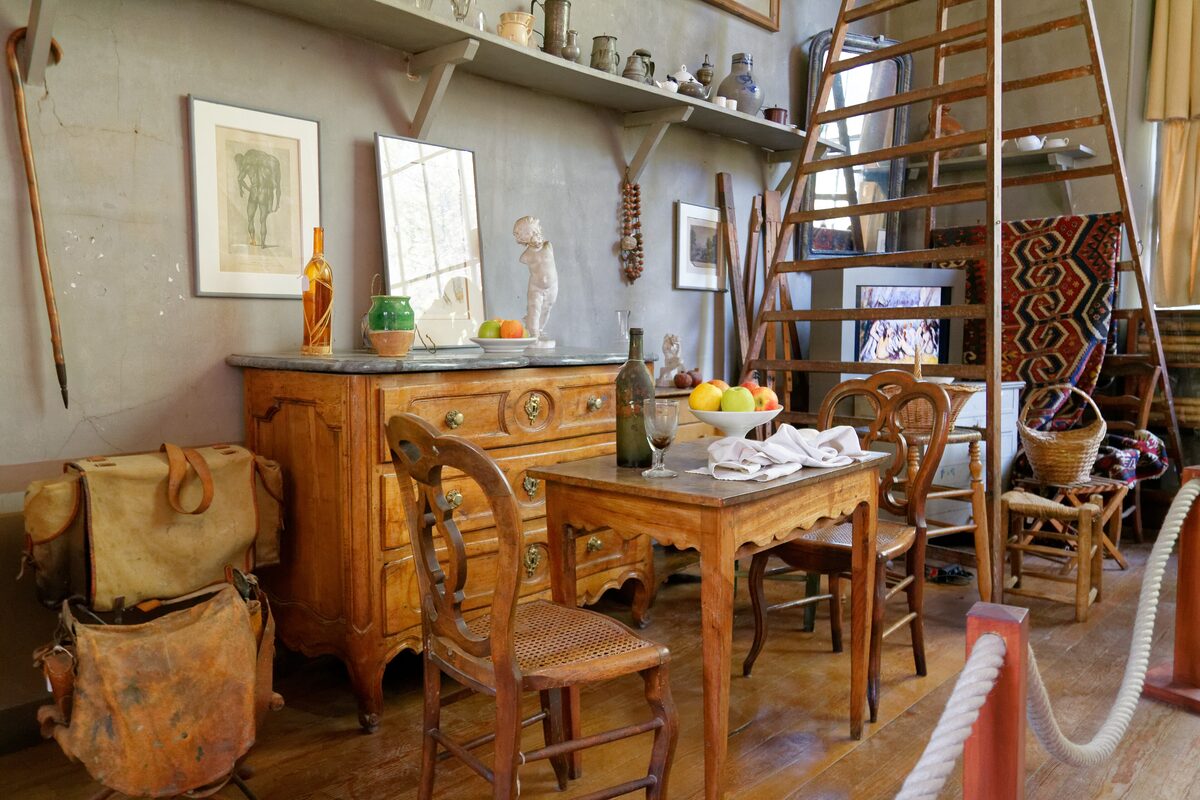 Paul Cézanne's studio at Les Lauves, with a wooden table and a bowl of fruit, a tall wooden ladder and his still-life props