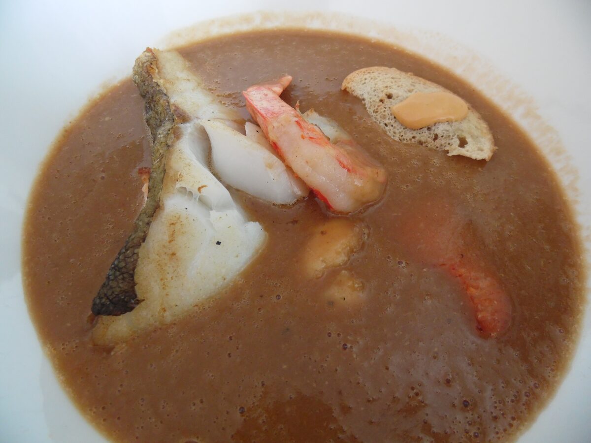 A bowl of bouillabaisse, the fish stew of Marseille, with a fillet of white fish, shellfish and a slice of bread