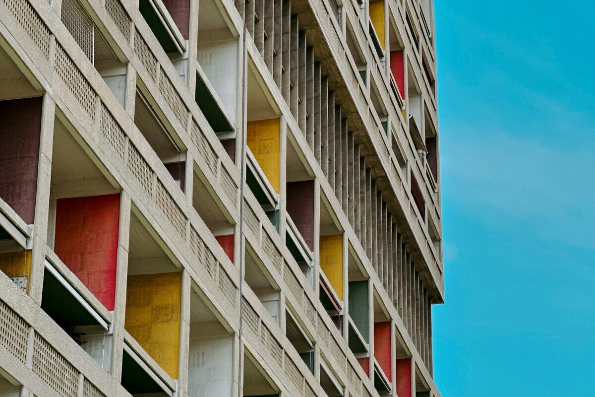 Detail of the Cité Radieuse facade: concrete loggias with red, yellow and brown painted back walls against a blue sky