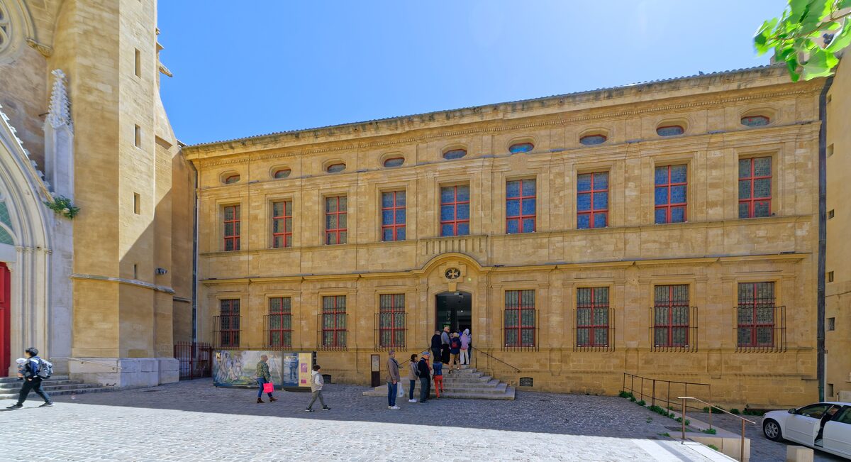 The yellow stone facade of the Musée Granet in Aix-en-Provence, with visitors on the steps