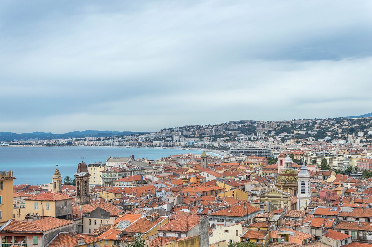 Red rooftops of the old town of Nice above the bay, under a cloudy sky