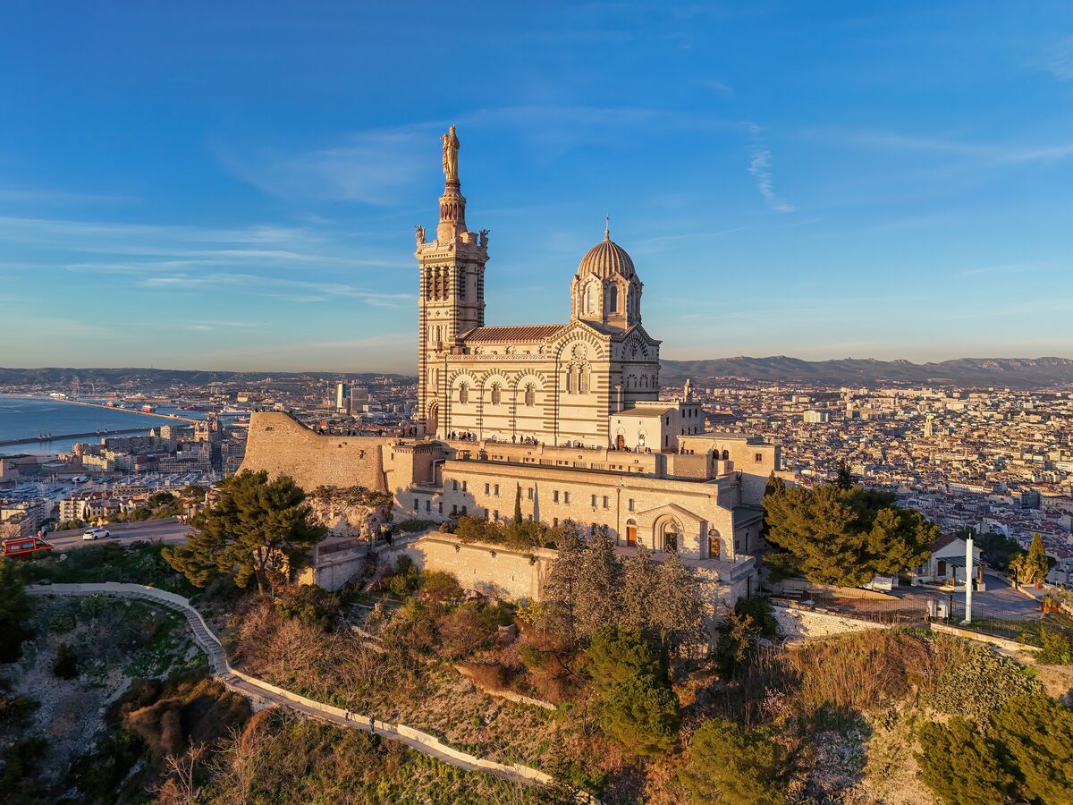 The basilica of Notre-Dame de la Garde on its hill, lit by the setting sun, with the city and sea below