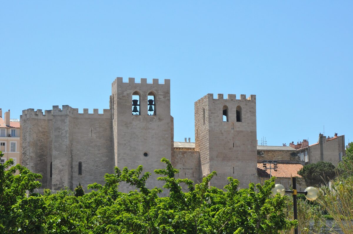The fortified bell tower and crenellated walls of the Abbaye Saint-Victor against a blue sky