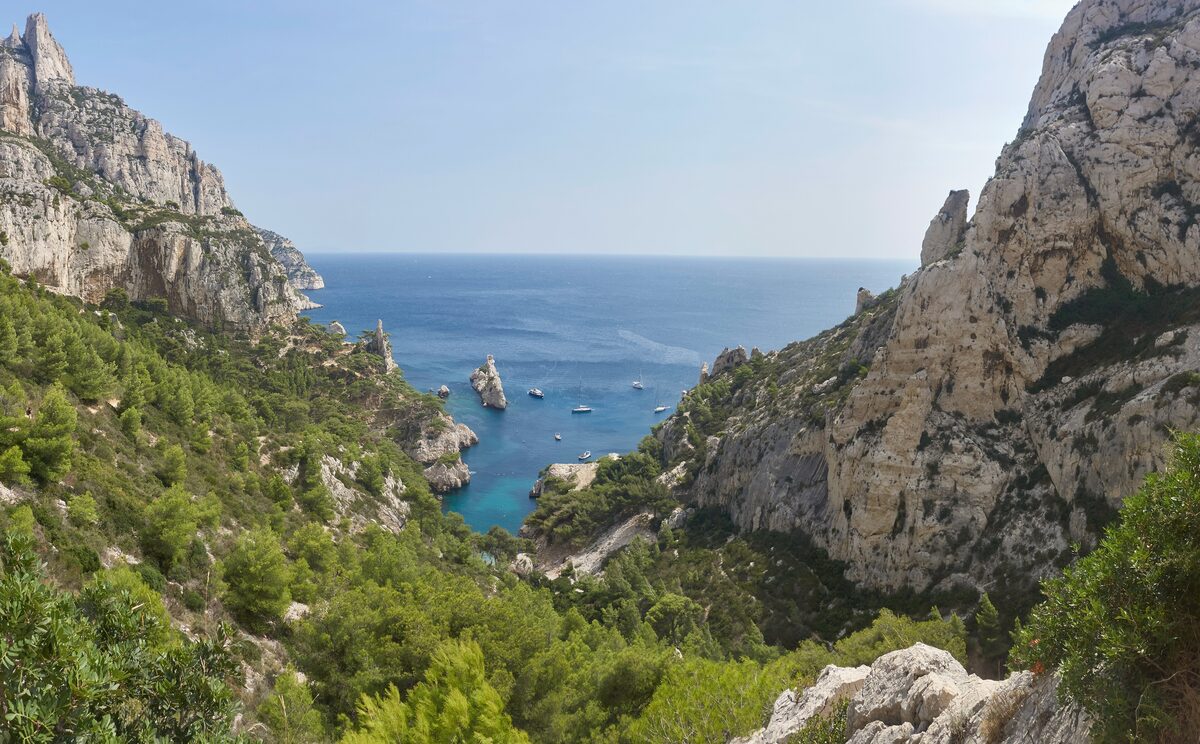The limestone cliffs above the Sugiton calanque, with the sea and boats in the bay far below