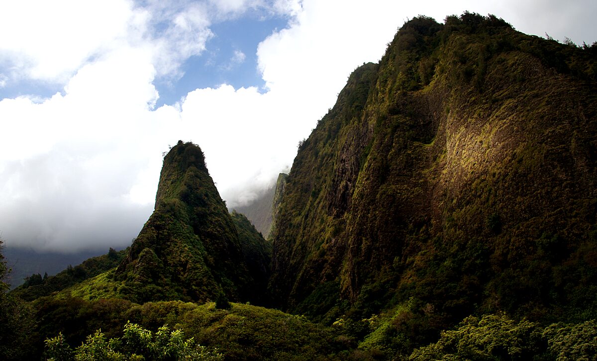 The green ʻĪao Needle rising beside steep forested cliffs in ʻĪao Valley