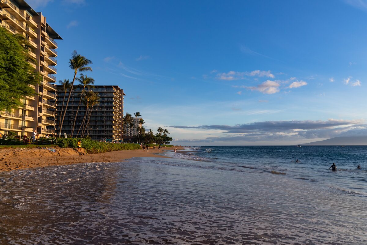 Kāʻanapali Beach with blue sky, shallow surf and hotels behind the sand