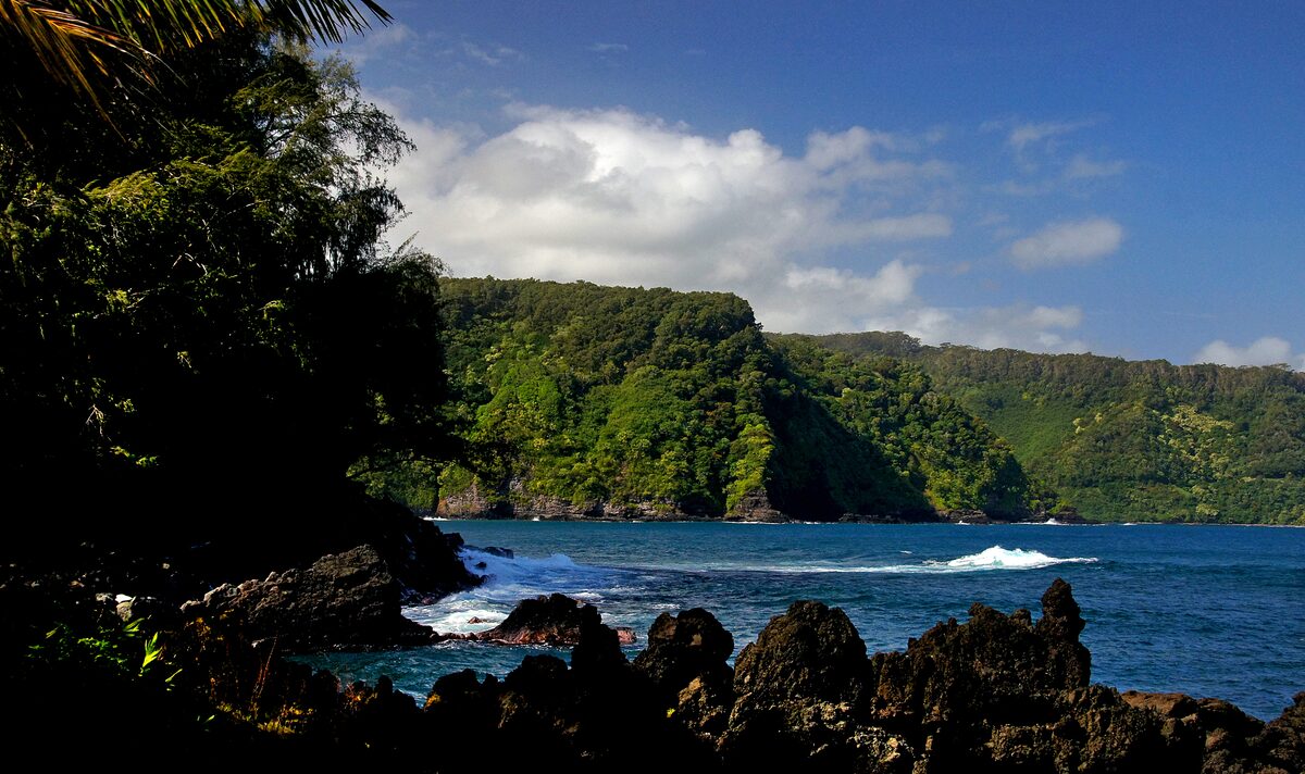 Green sea cliffs beyond the black lava rocks of the Keʻanae coast
