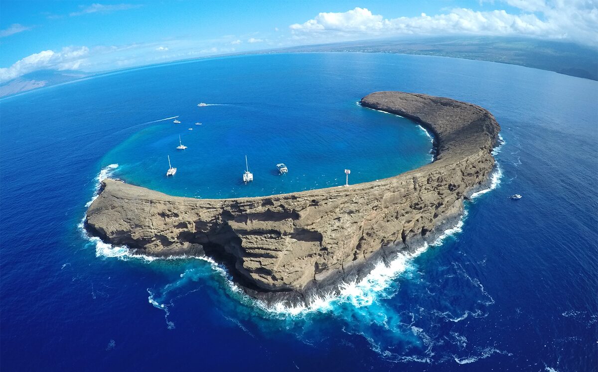 Aerial view of crescent-shaped Molokini crater with boats moored in its sheltered bay
