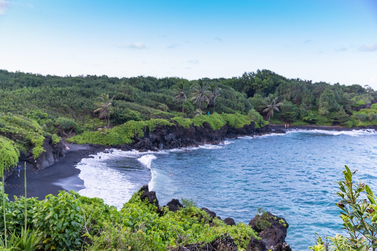 The black sand cove at Waiʻānapanapa, framed by green forest and blue sea
