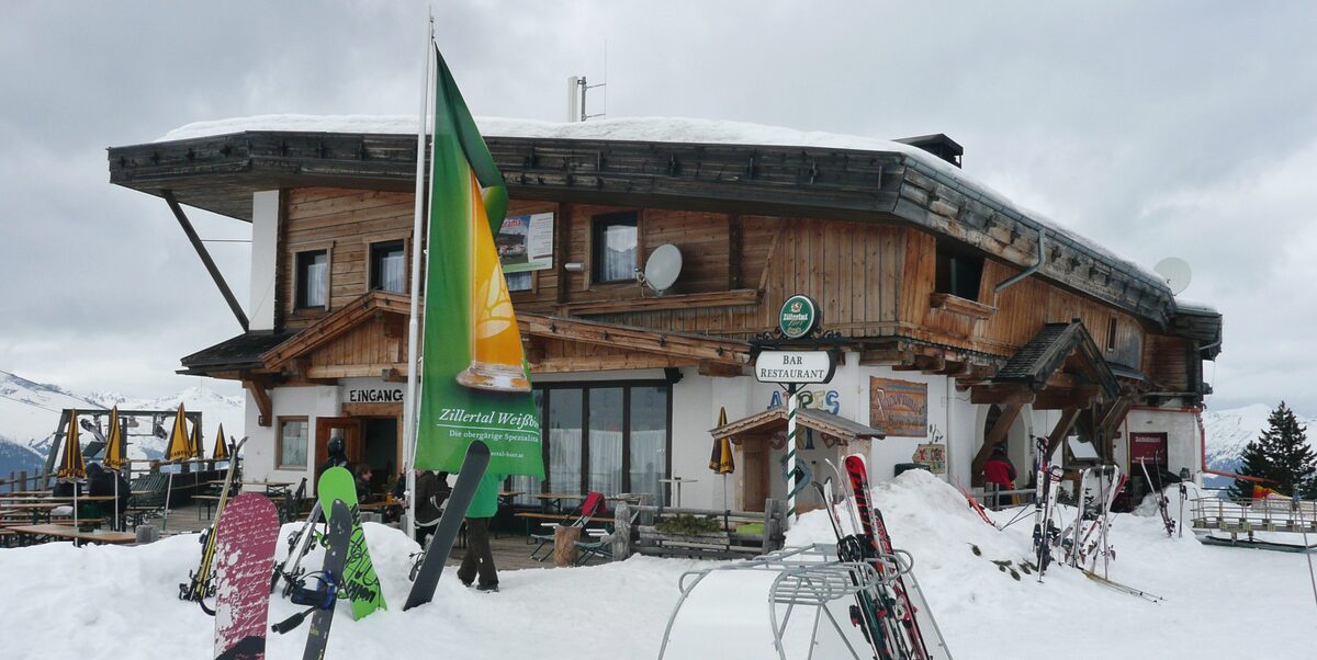 A mountain hut on the Ahorn in the snow, with skis and snowboards stuck in the drift outside