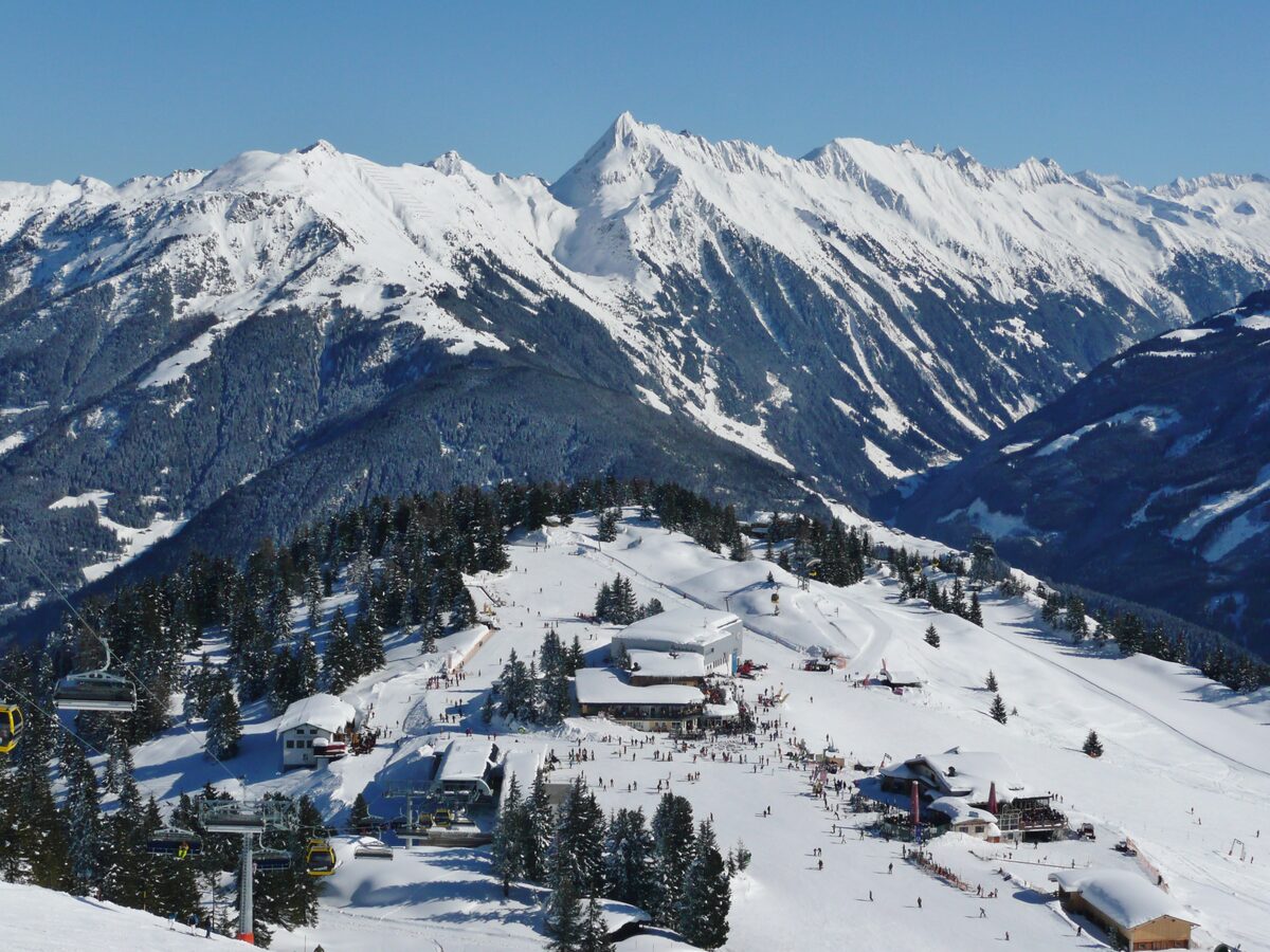 The Penkenbahn mountain station at 1,800 m in deep snow, with skiers around the buildings and the Zillertal Alps above