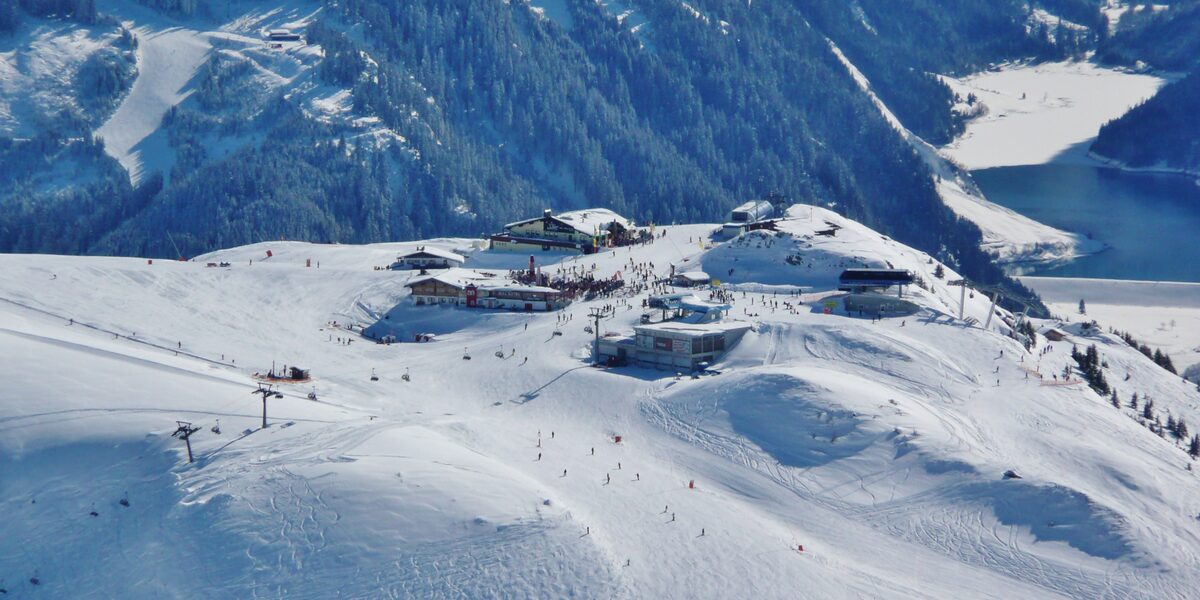 Huts and a chairlift on the snowy Penkenjoch, with a reservoir lake in the valley on the right