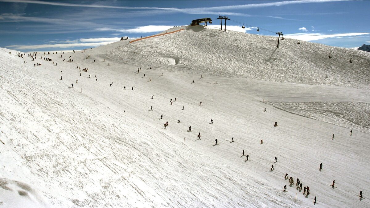 A wide groomed piste on the Rastkogel in snow, with skiers spread across it and a lift station at the top