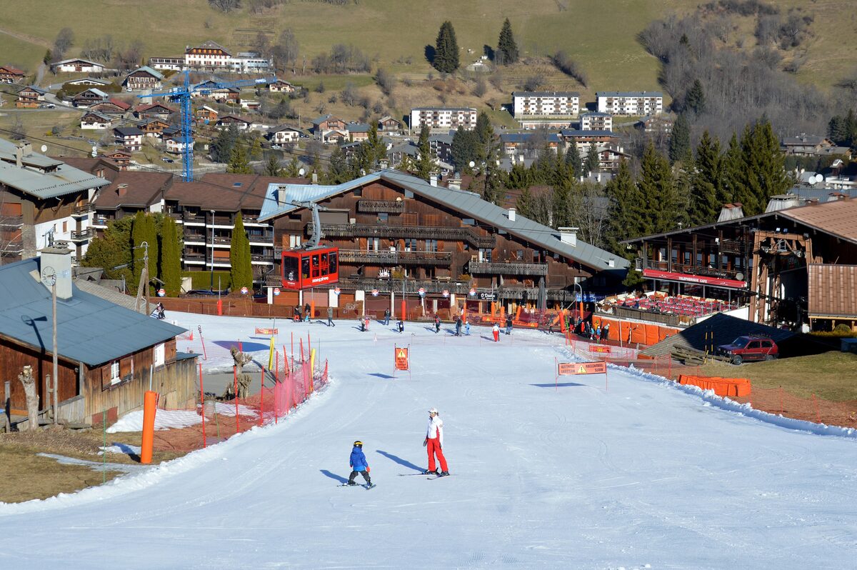 Beginners and families on the Rochebrune snow front, with chalets and a lift line behind