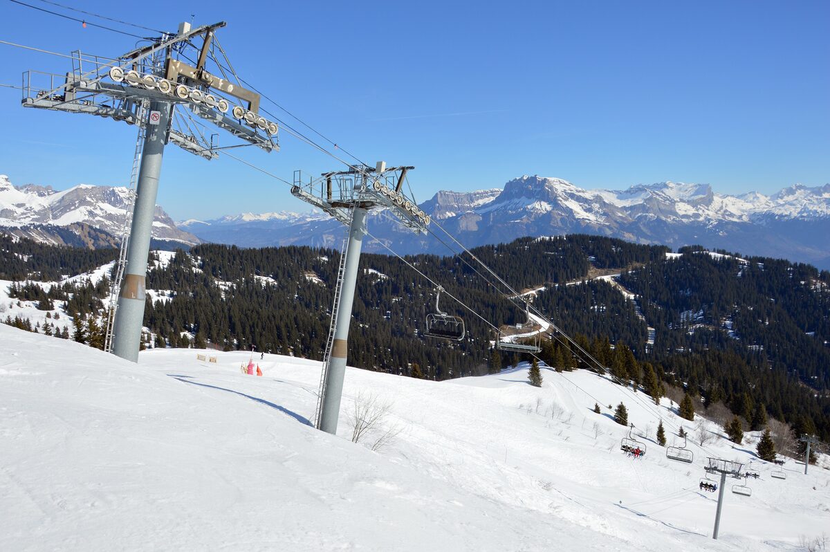 Chairlift towers on the Christomet with snow on the piste and the Faucigny range beyond