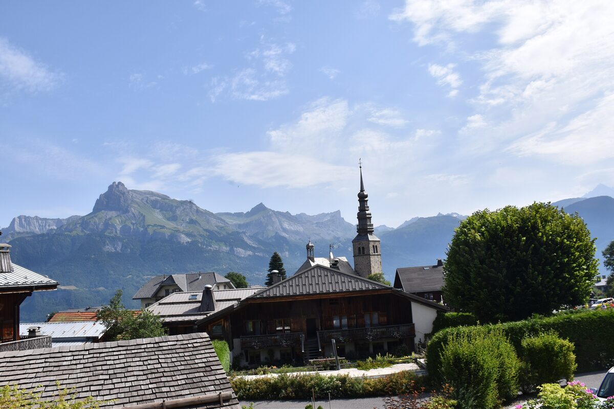 The bell tower of the Saint-Nicolas church in Combloux with the Aravis peaks behind
