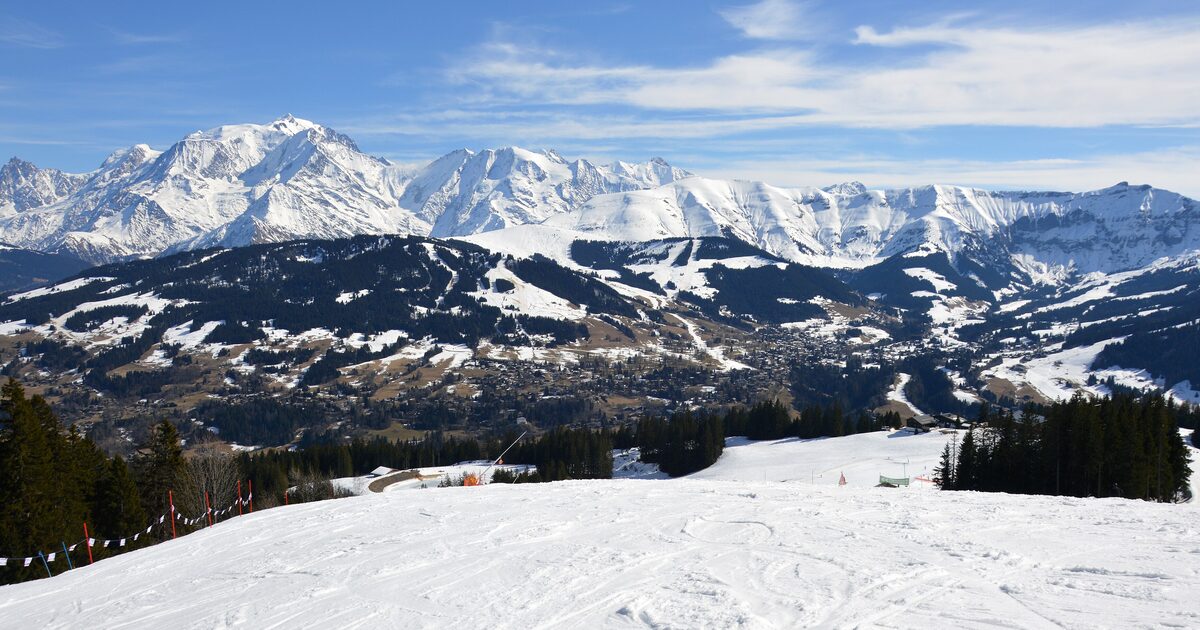 Groomed snow slope above Megève with Mont Joly and the Mont Blanc massif across the valley