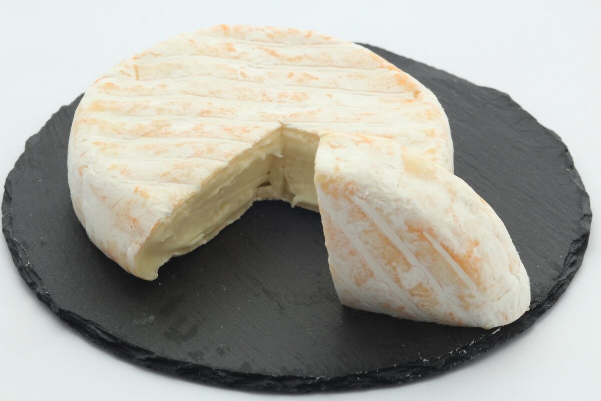 A round of reblochon with one wedge cut out, on a slate board