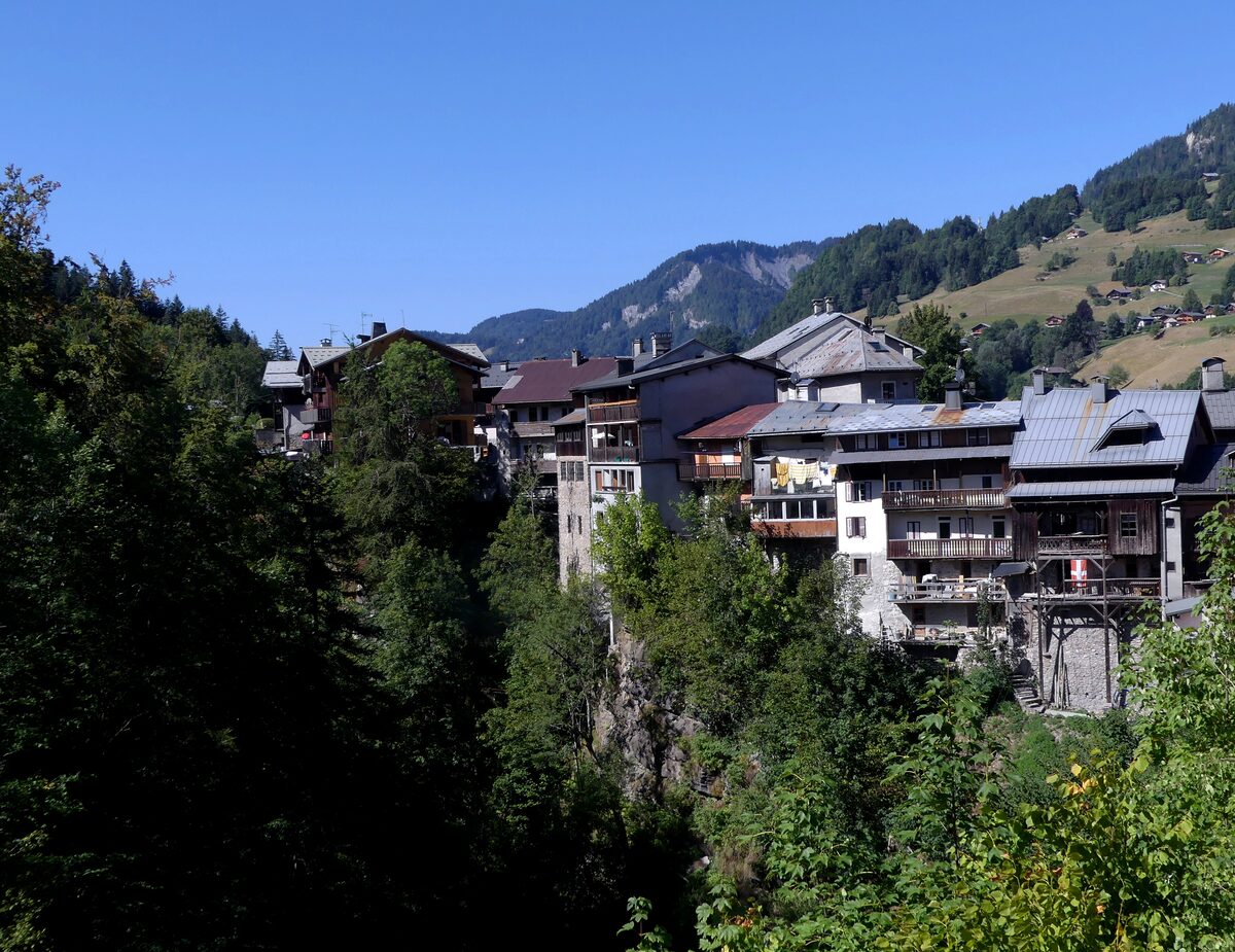 Houses of Flumet on the wooded slope above the Arly river on a sunny morning