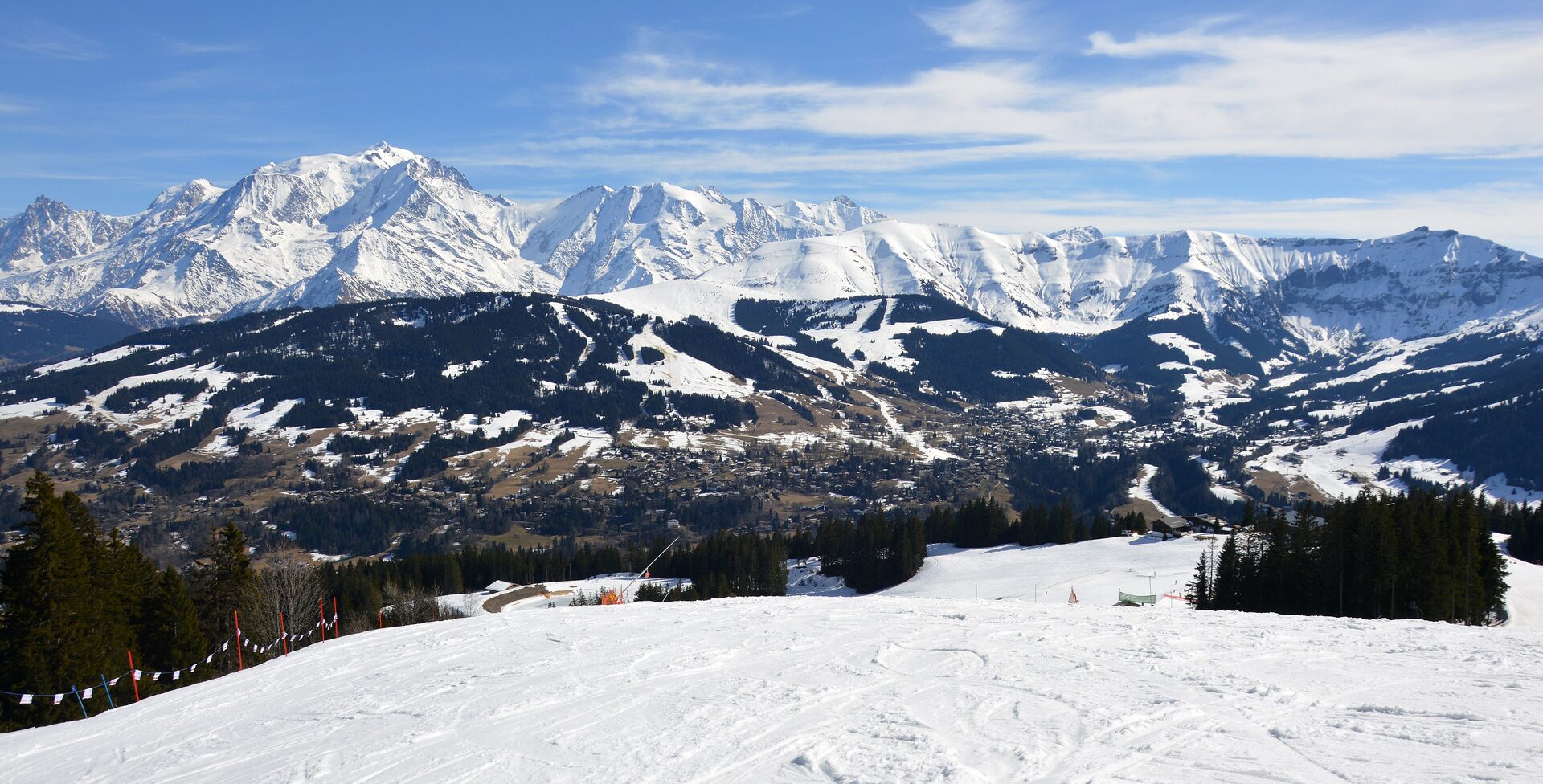 Groomed snow slope above Megève with Mont Joly and the Mont Blanc massif across the valley
