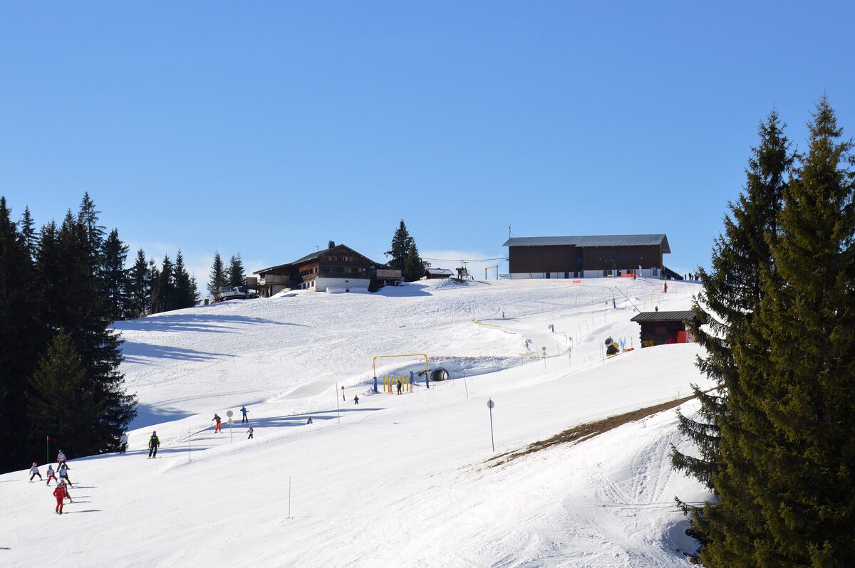 Snowy piste and the top station of the Jaillet gondola, with skiers below