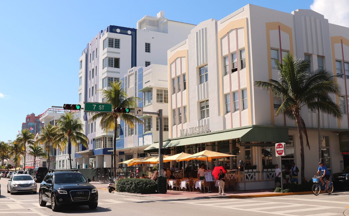 The Majestic Hotel and its neighbors on Ocean Drive at 7th Street, pale Art Deco facades with colored trim, palms and a street cafe