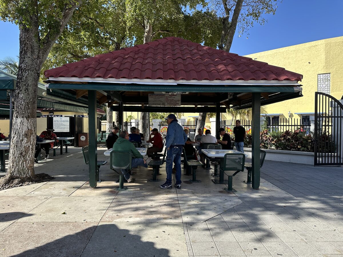 The red-roofed pavilion of Máximo Gómez Domino Park in Little Havana, with players at tables in the shade