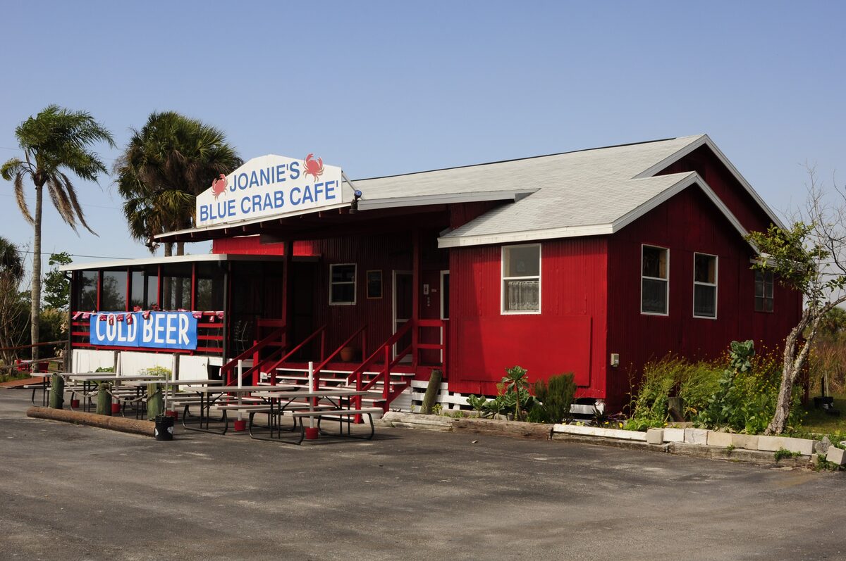 Joanie's Blue Crab Cafe, a red wooden building with a Cold Beer sign, picnic tables and palms by the Tamiami Trail